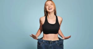Smiling woman showing loose jeans after successful Medical Weight Loss in Martinsville, VA